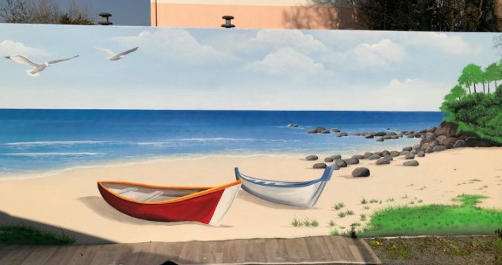 Paysage de plage avec deux barques colorées, mer calme et ciel dégagé.