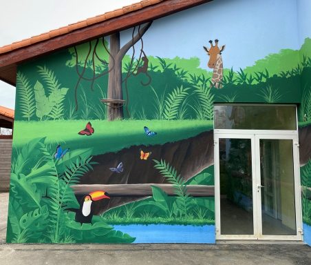 Murale coloré représentant des animaux de la forêt tropicale, avec un toucan et une girafe.