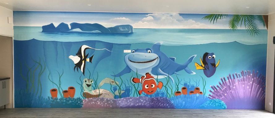 Murale coloré sous-marin avec des poissons, coraux et une grande baleine souriante.