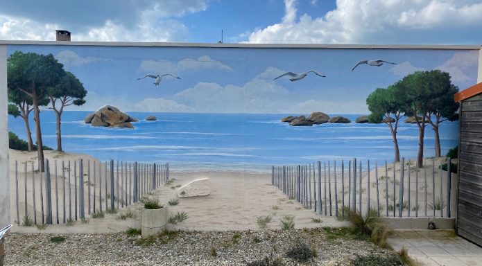 Murale représentant une plage avec des arbres, des oiseaux et des rochers au loin.