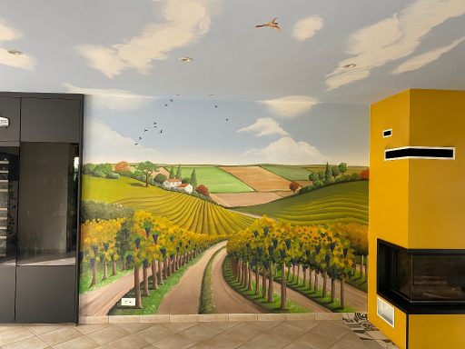 Fresque d'un paysage viticole avec des vignes, collines et un ciel bleu. Mur jaune à droite.
