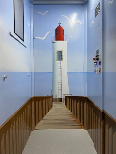 Mur peint représentant un phare rouge sur fond bleu, avec des oiseaux et une jetée.