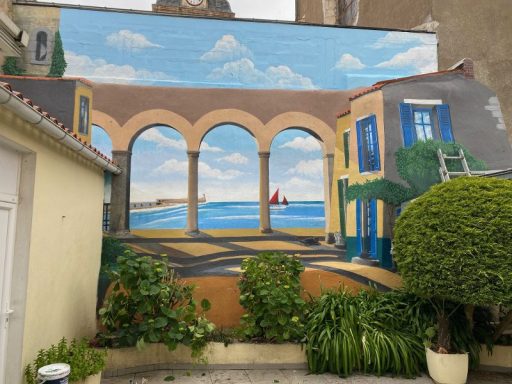 Fresque murale représentant un paysage côtier avec un arc et des bâtiments colorés.