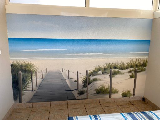Paysage côtier avec une passerelle menant à la plage, ciel bleu et sable.